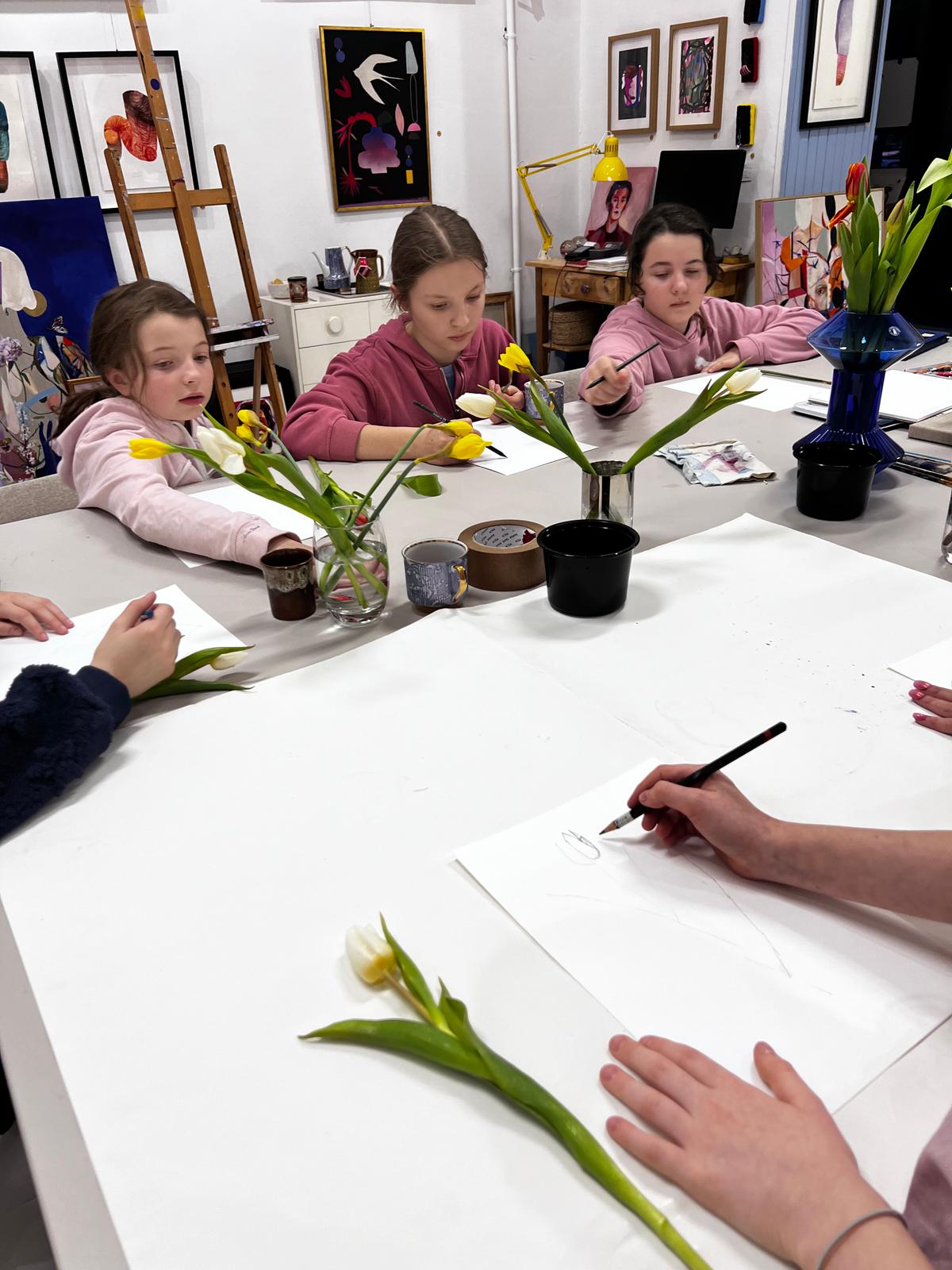 Dzieci rysują kwiaty tulipanów w artystycznym studio podczas zajęć malarskich.