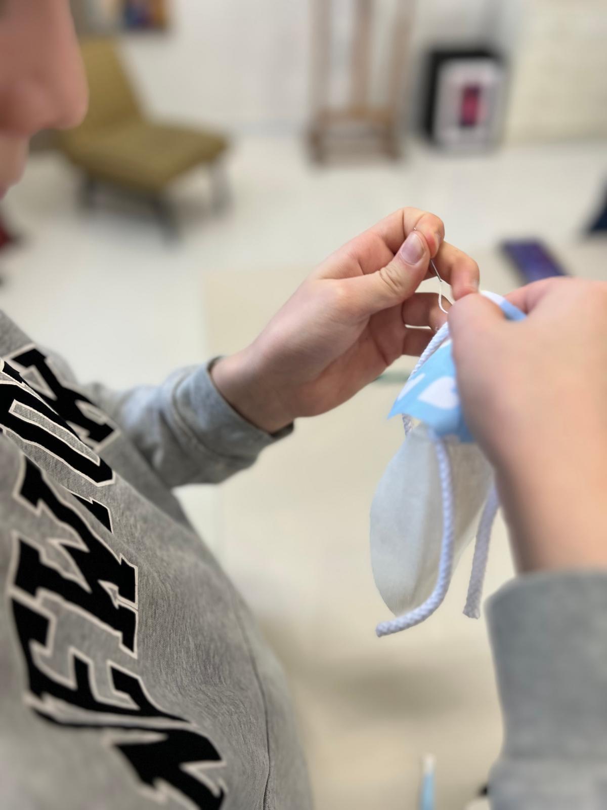 Dziecko trzyma w rękach niebieską wstążkę lub sznurek w pomieszczeniu.