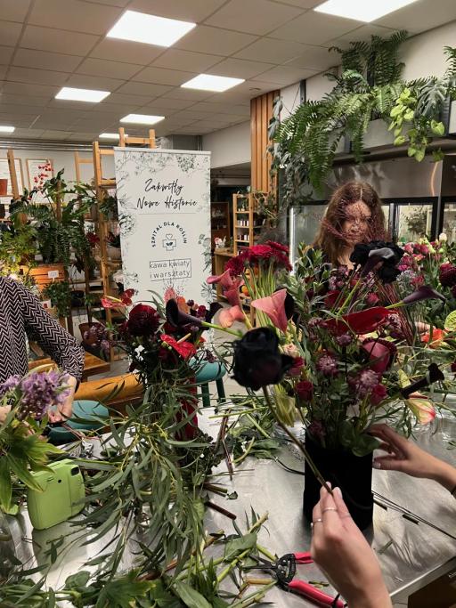 Kobieta przygotowuje bukiety kwiatów w kwiaciarni, otoczona kolorowymi kwiatami i zielenią.