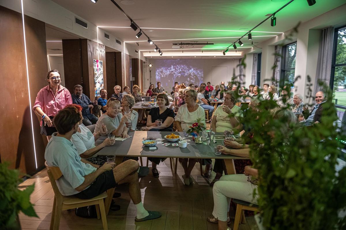 Uczestniczki warsztatu Fundacji Czerwony Krakowiak podczas degustacji naparów z roślin, w przytulnej sali ze zielenią i nowoczesnym oświetleniem.