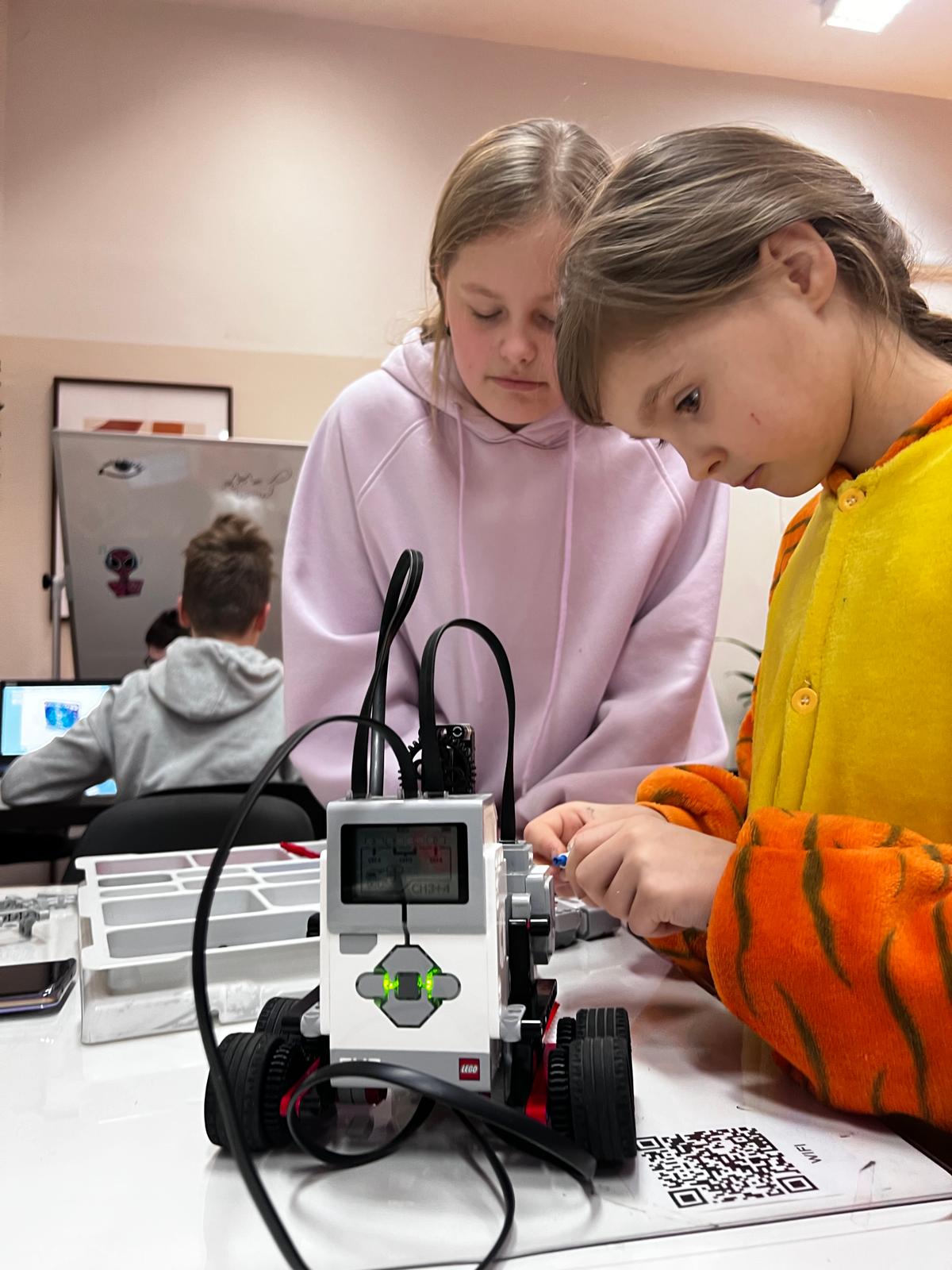 Dzieci pracują nad robotem LEGO w klasie, uczą się programowania i robotyki podczas zajęć edukacyjnych.