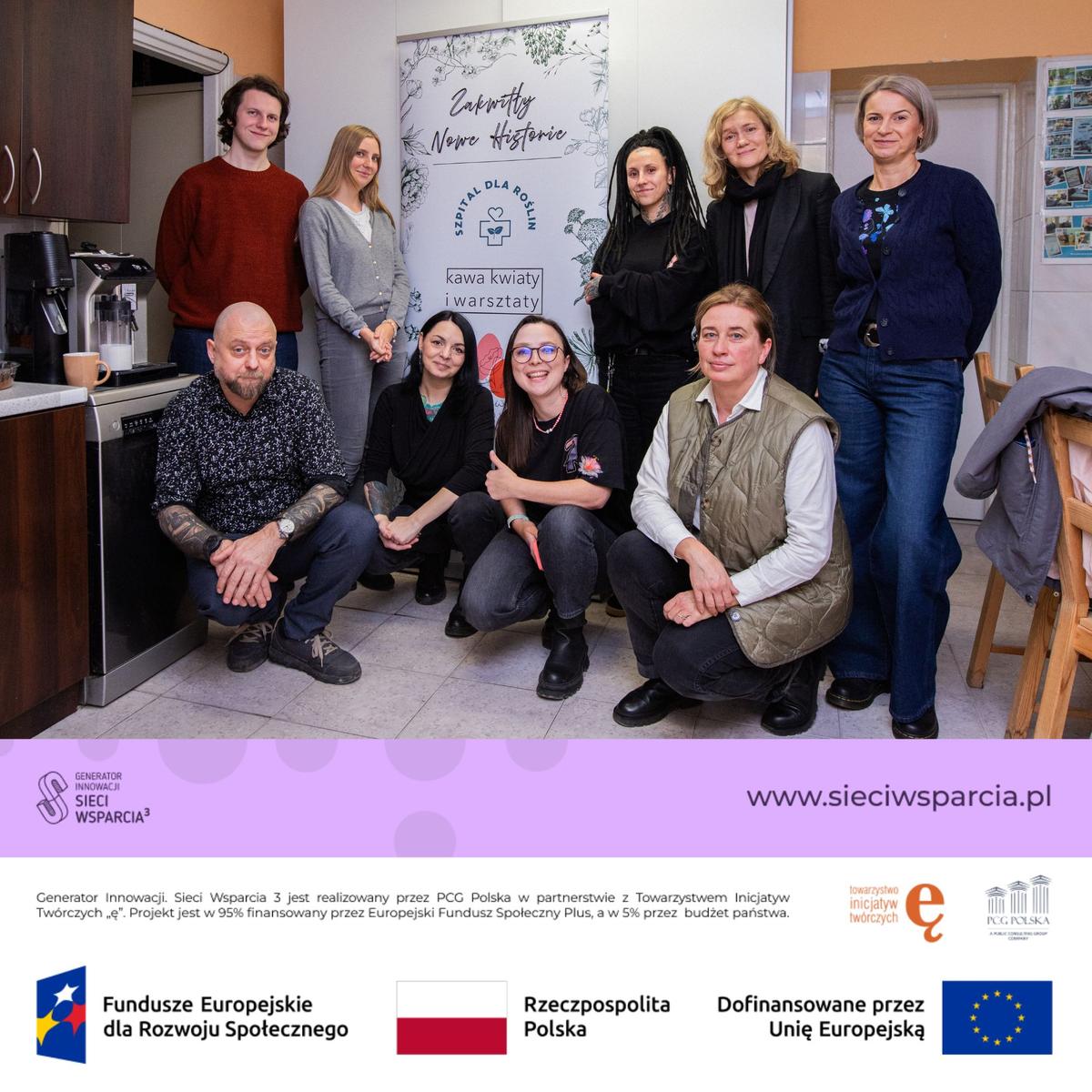 Grupa dziewięciu osób pozuje do zdjęcia w kuchni podczas spotkania projektu "Sieci Wsparcia 3" finansowanego przez Unię Europejską.