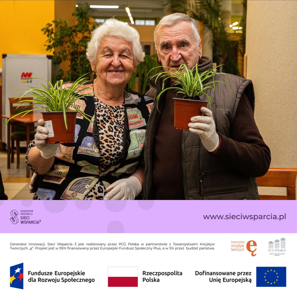 Dwoje seniorów trzyma doniczki z roślinami podczas wydarzenia promującego polski program innowacyjny wsparty przez Unię Europejską.