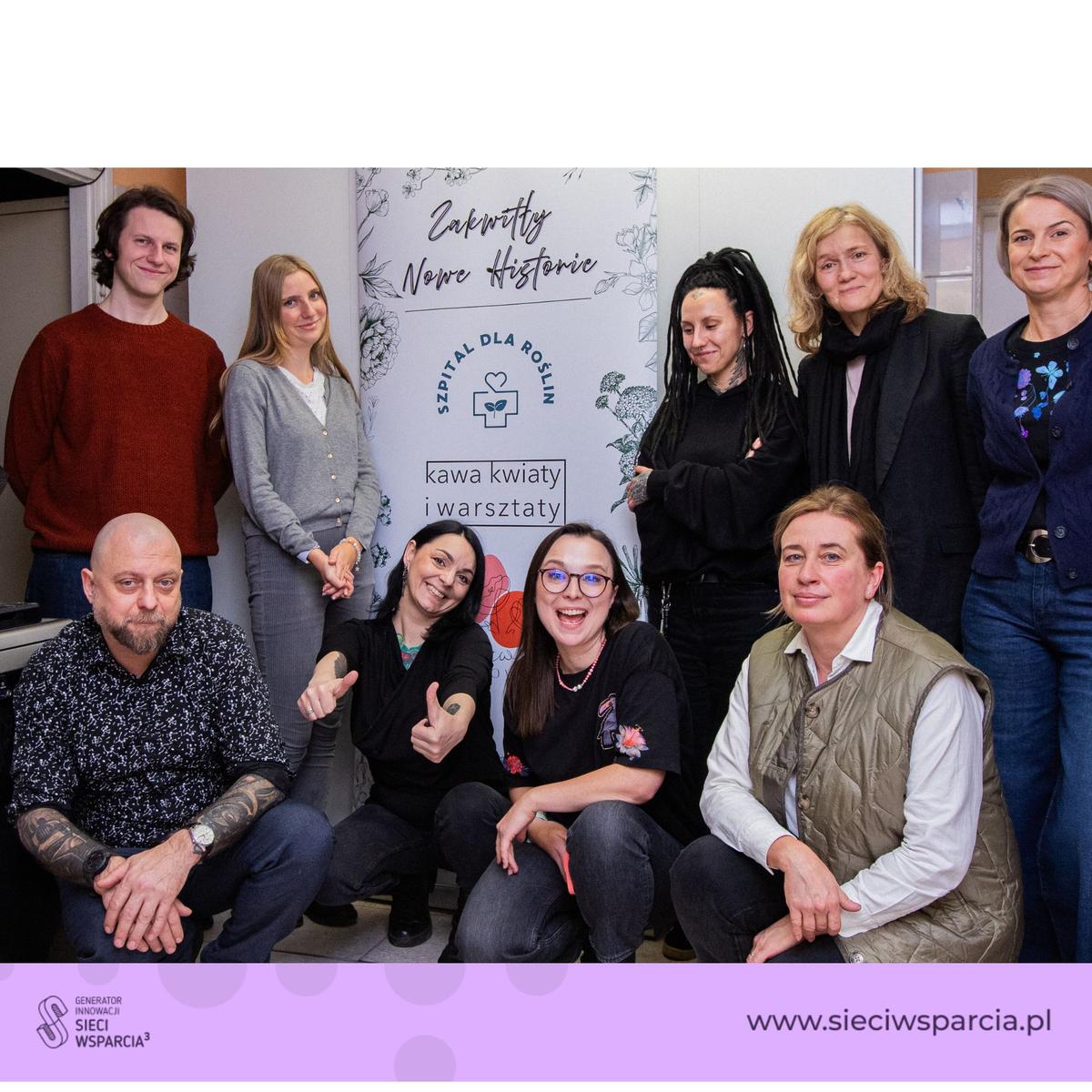 Grupa osób pozuje do zdjęcia przy banerze organizacji Szpital dla Roślin przed logo Sieci Wsparcia.